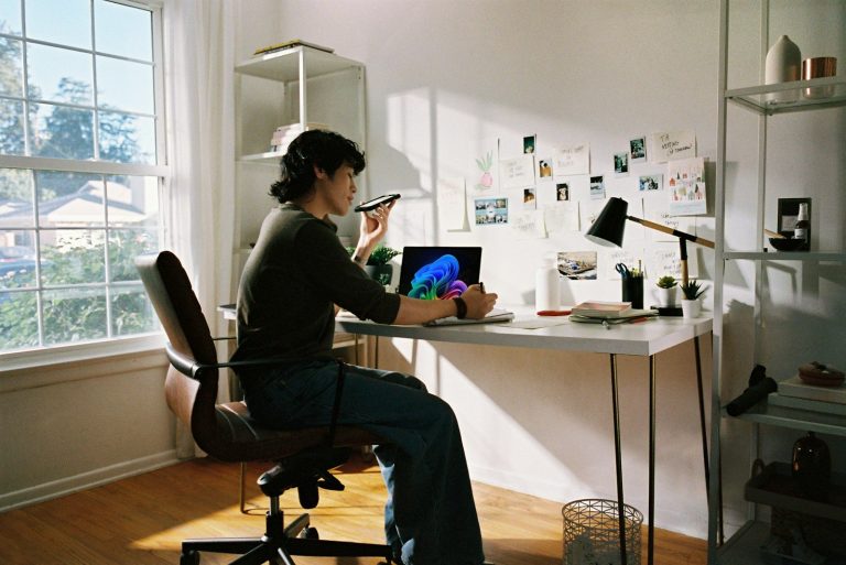 Woman working at desk with laptop and phone.